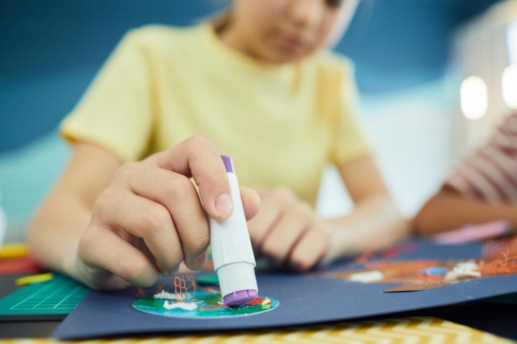 A child using glue for an art project, focusing on creativity and hands-on learning.